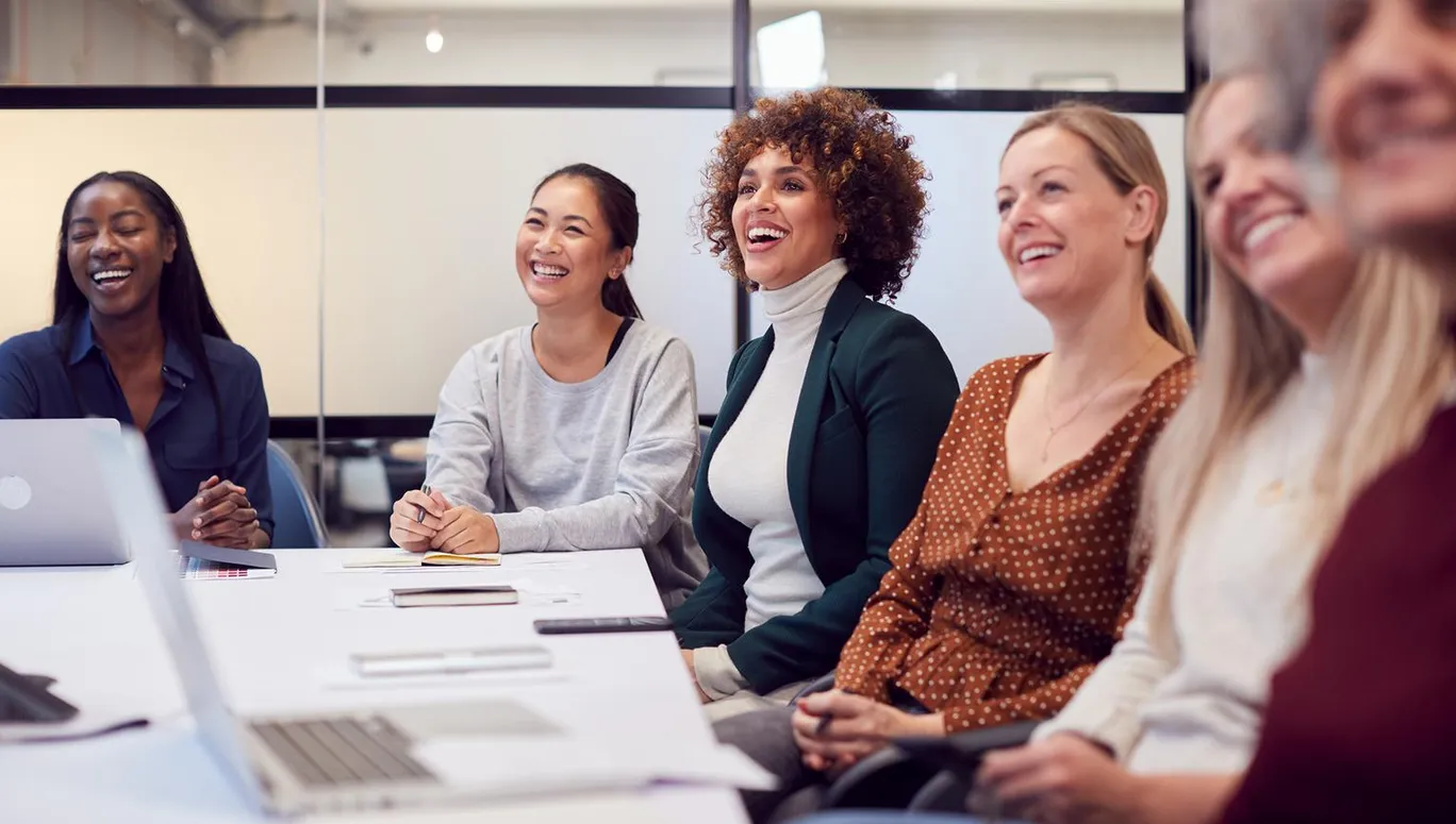 Line Of Businesswomen In Modern Office Listening To Presentation By Colleague
