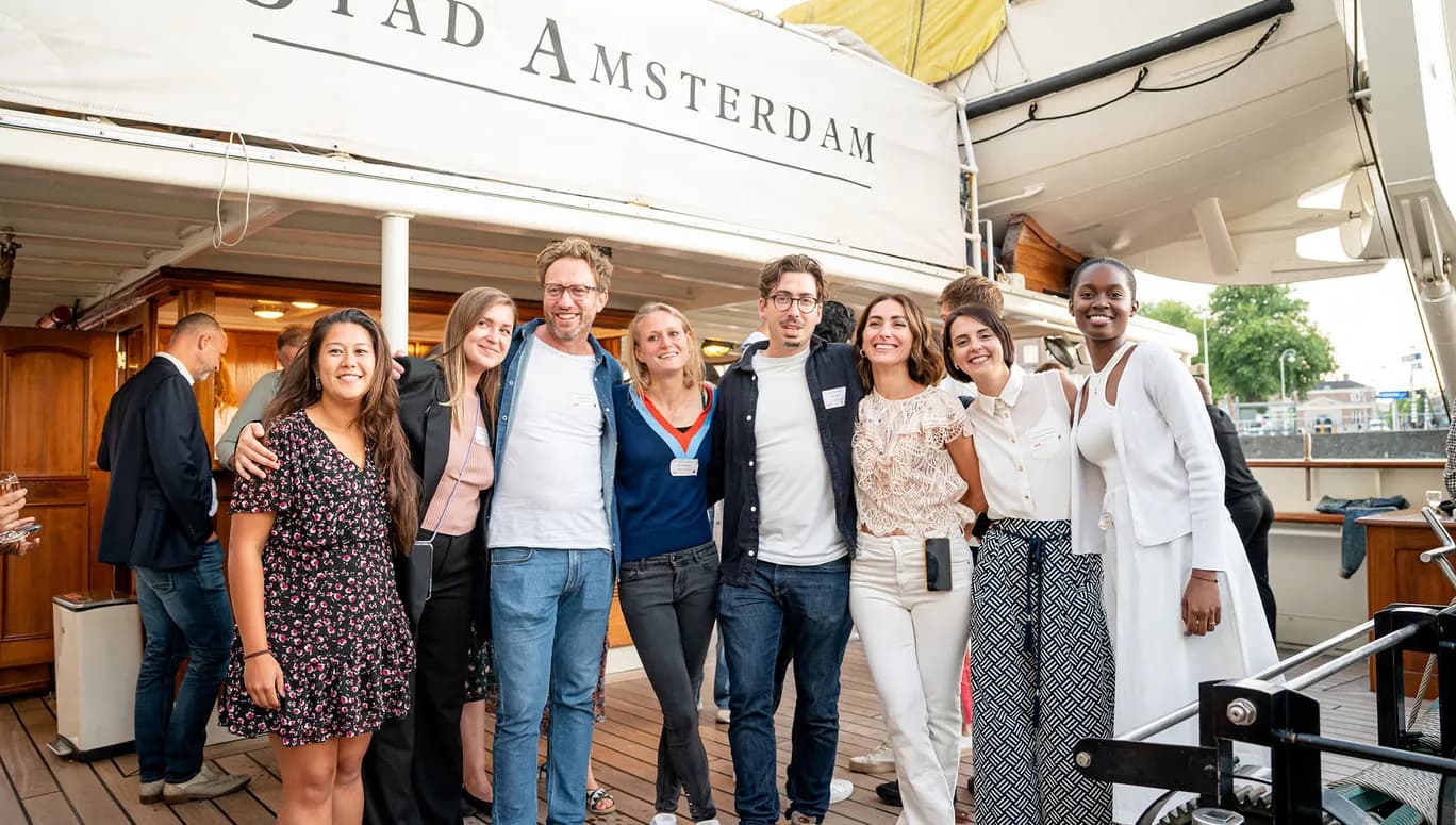 Photograph of StartupAmsterdam team having summer drinks, with "Stad Amsterdam" sign in background.