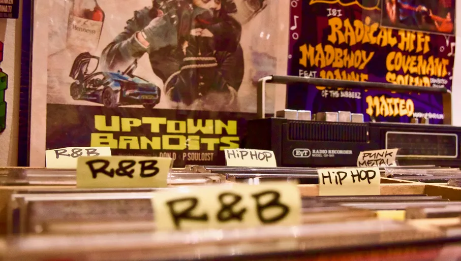 Outside the shop a man in a wheelchair looking inside, vinyls inside the shop, funny objects