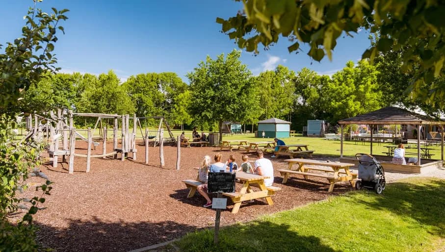 A family sits at the picnic tables next to the playground of Landgoed de Olmenhorst in Lisserbroek
