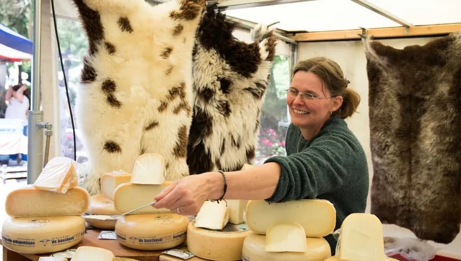 Woman shares a cheese sample to a costumer at the Pure Markt